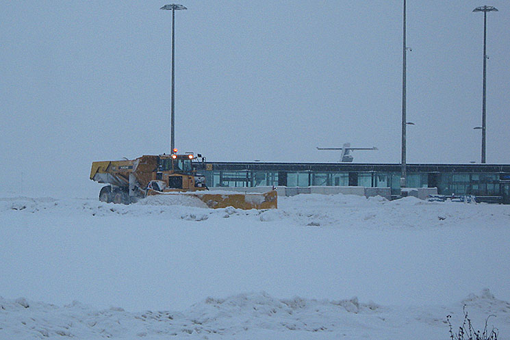 Engin en action sous la neige sur piste d'aéroport